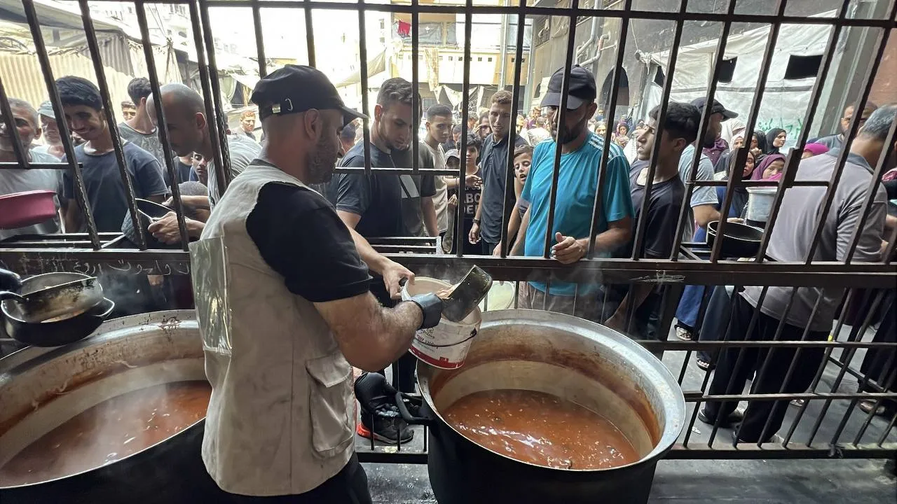 Een veldmedewerker van Dutch Aid Foundation schept een warme maaltijd op bij een distributiepunt in Gaza.