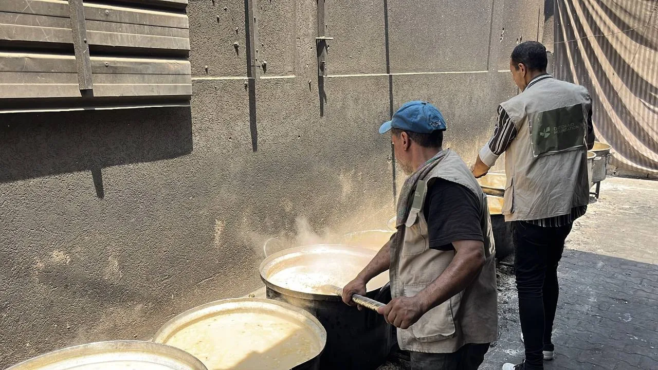 Twee veldmedewerkers van Dutch Aid Foundation verzorgen grote kookpannen in Gaza.