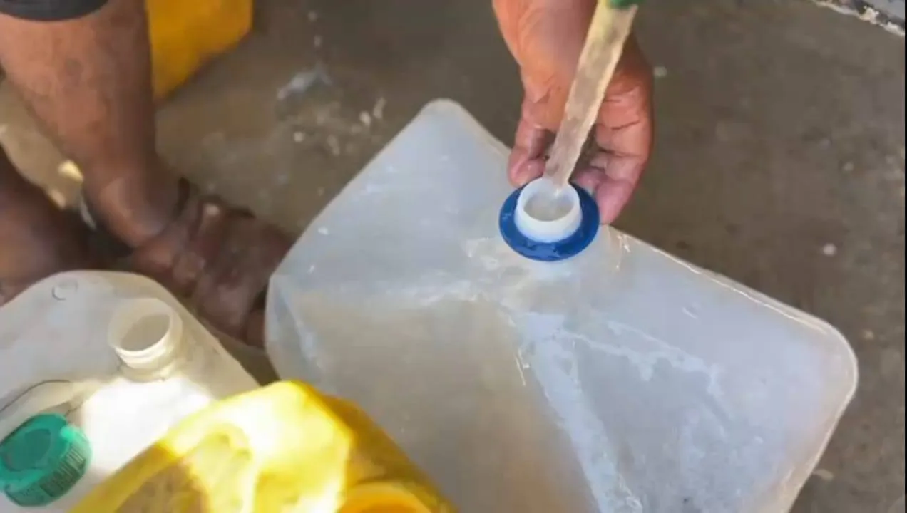 Een hand vult een grote watercontainer in Gaza.